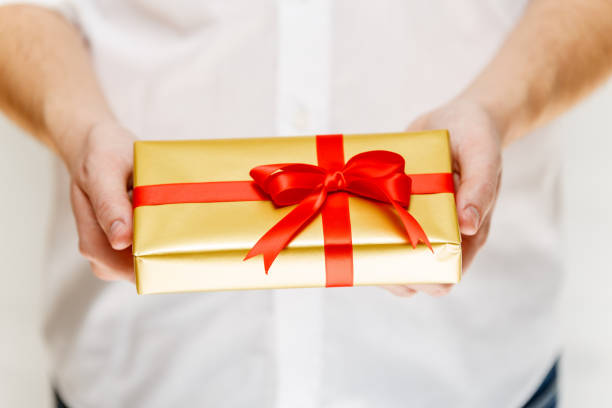 istock Male hands holding a gift box with ribbon. 665357670