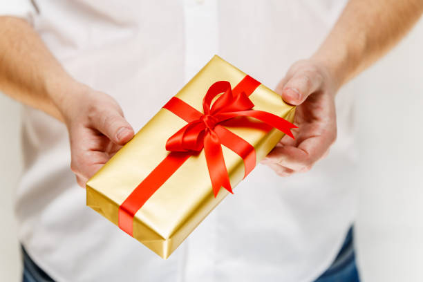 istock Male hands holding a gift box with ribbon. 665357854