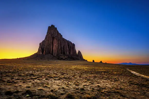 Sunset above Shiprock. Shiprock is a great volcanic rock mountain rising high above the high-desert plain of the Navajo Nation in New Mexico, USA