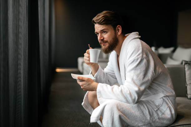 hombre guapo tomando té y relajante en bata de baño - albornoz fotografías e imágenes de stock