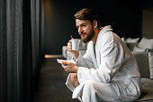 Handsome man drinking tea and relaxing in bathrobe