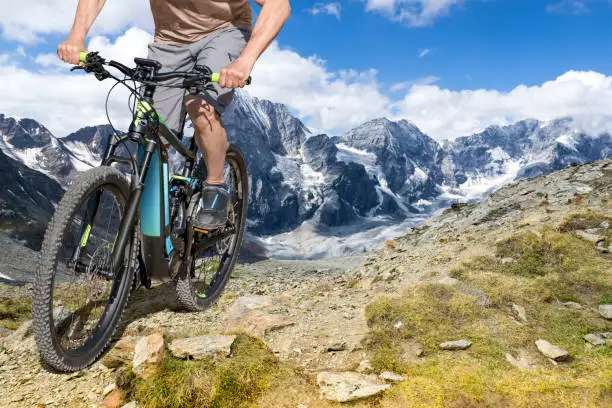 Single mountain bike rider on E bike rides up a steep mountain trail.