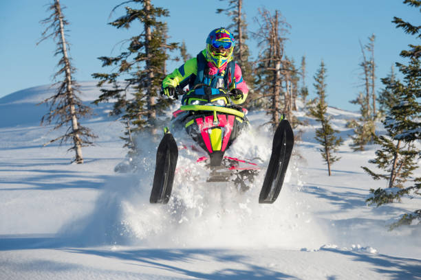 motoneige extrême sur la neige profonde dans la forêt de sapin. - snow jumping snowmobiling sled photos et images de collection