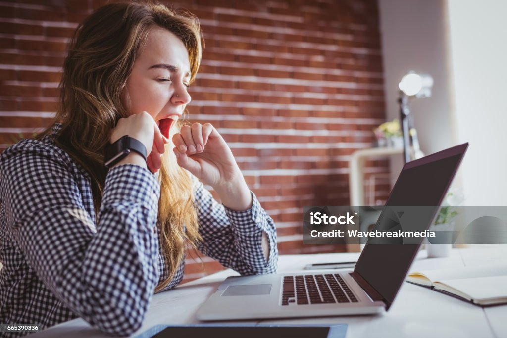 Young hipster businesswoman yawning Young hipster businesswoman yawning at her desk in office Yawning Stock Photo