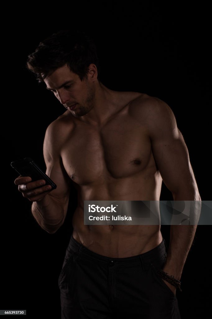 Handsome shirtless muscular young man using cell phone Handsome shirtless muscular young man using cell phoneHandsome shirtless muscular young man using cell phone Men Stock Photo