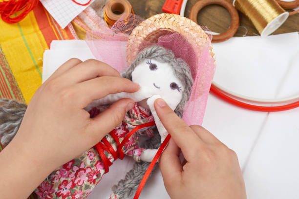 istock child hand making dress for handmade doll, learn to sewing 665394780