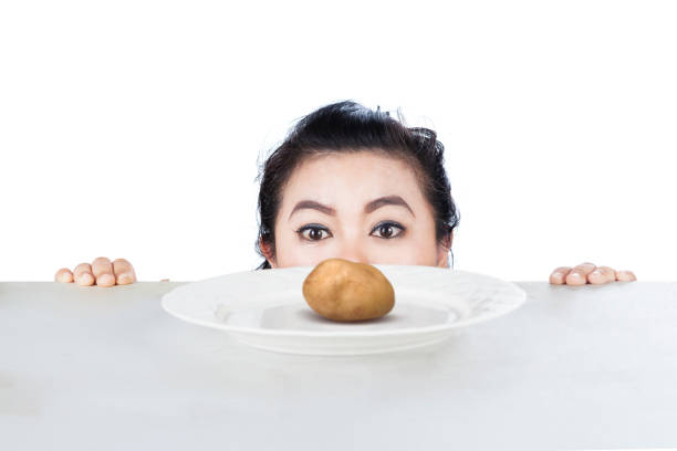 Picture of woman peeping boiled potato in the studio, isolated on white background