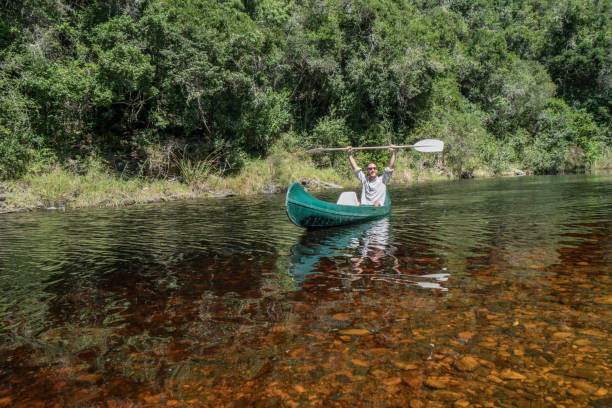 istock Cheerful young man in canoe, arms outstretched 665405182