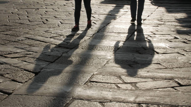 istock Silhouettes of people on the cobblestone pavement 665405680