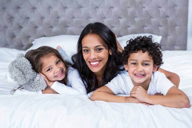 istock Smiling mother with children on the bed 665407580