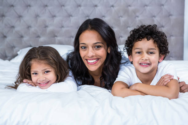 istock Smiling mother with children on the bed 665409798