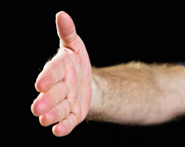 istock Hand signs:  hand outstretched against black for handshake 665411058