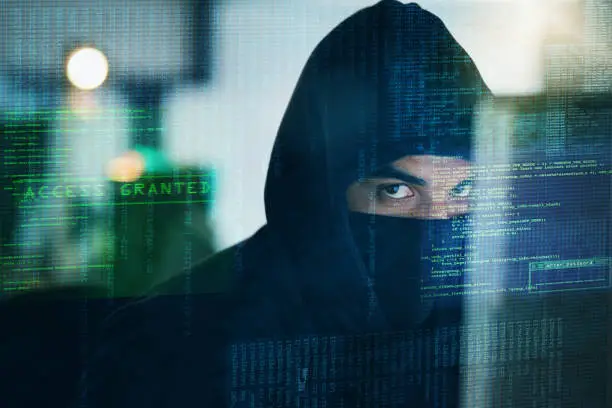 Portrait of a serious computer hacker hacking into a computer in an office