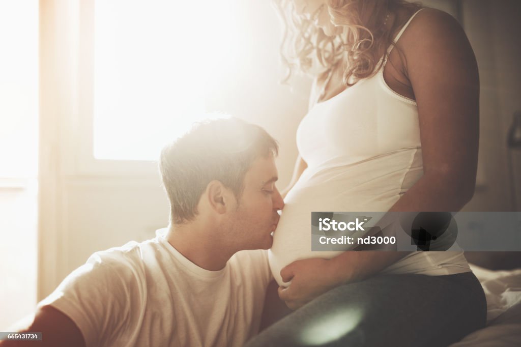 Husband kissing  newborn through wife belly Pregnant Stock Photo