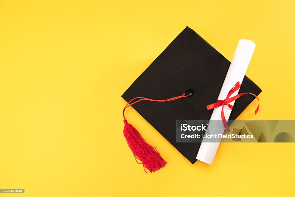 Top view of graduation mortarboard and diploma on yellow background, education concept Mortarboard Stock Photo