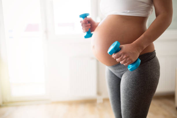 Pregnant woman training with dumbbells to stay active Pregnant woman training with dumbbells to stay active serbia and montenegro stock pictures, royalty-free photos & images