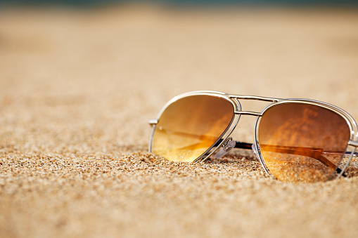 Concept image of summer holidays with beach scene in sunglasses on sand