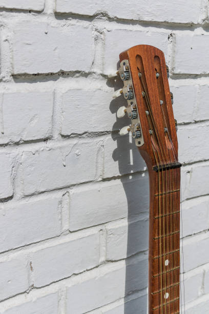 istock Acoustic guitar headstock against white brick wall 665444334