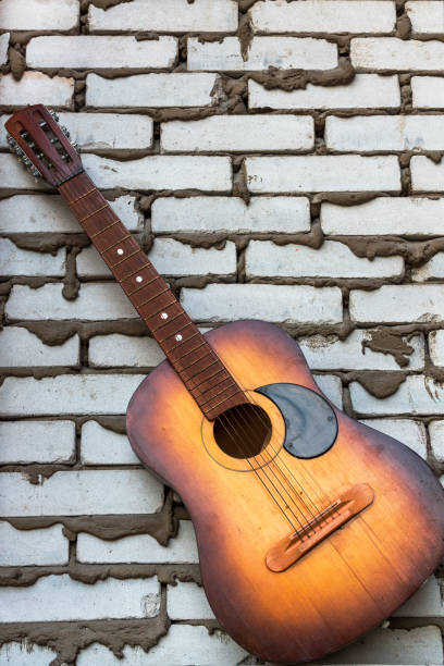 istock Acoustic guitar resting against a white  brick background 665444344
