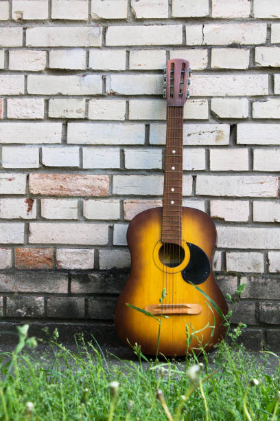 istock Acoustic guitar resting against a white brick wall 665444346