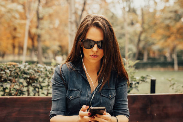 istock Beautiful woman is sitting on the bench and using phone 665453298