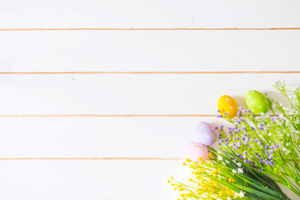 istock Spring flowers and easter eggs on white wooden table. View from above. 665456072