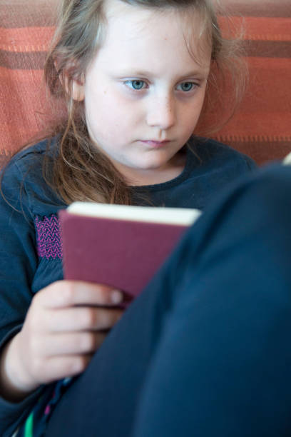 istock A little school girl reading a book. 665459918