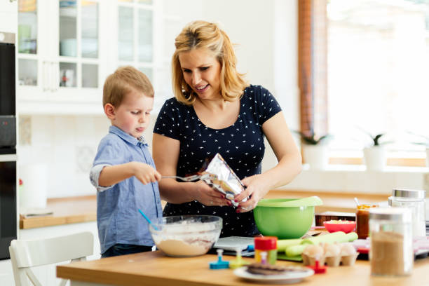 istock Smart cute child helping mother in kitchen preparing cookies 665460766