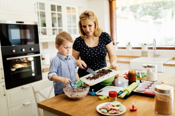 istock Smart cute child helping mother in kitchen preparing cookies 665460938