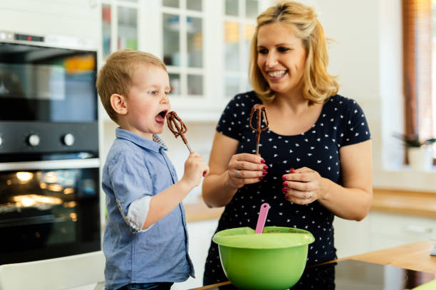 istock Smart cute child helping mother in kitchen preparing cookies 665461096