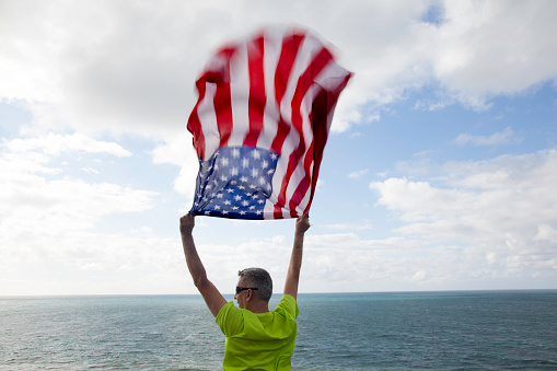 Man with American flag on the beach
