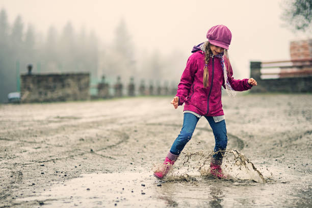 istock Little girl splashing in early spring puddle 665476558