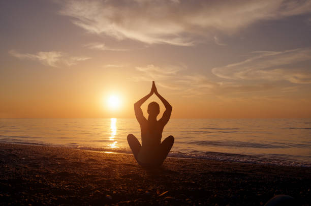 istock Silhouette young woman practicing yoga on the beach at sunset. 665482670