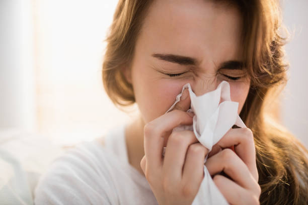 donna che si soffia il naso sul divano - cold and flu flu virus sneezing illness foto e immagini stock