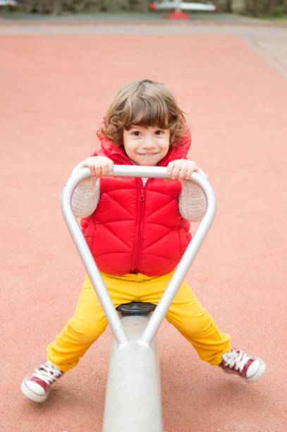 istock Little boy smiling on a playground teeter totter 665514958