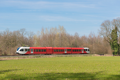 Red white colored train on a light rail track in the Achterhoek near Winterswijk in the Netherlands