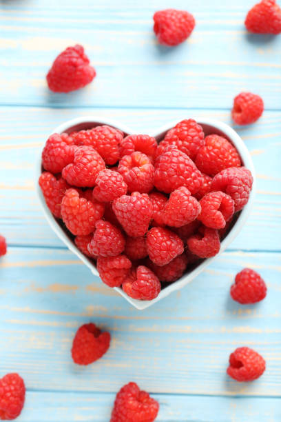 istock Red raspberries in bowl on a blue wooden table 665536000