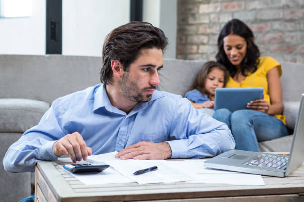 istock Serious man paying bills in living room 665543934