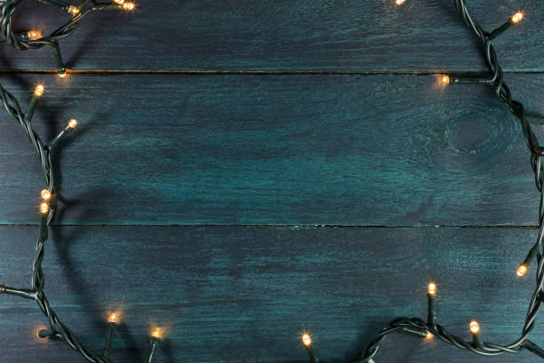 istock Fairy lights on a dark wooden texture, holiday background 665549412
