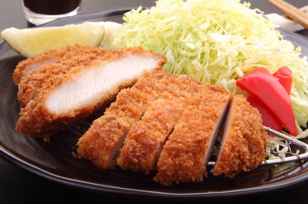 frittierte schweineschnitzel mit salat und zitrone, japanische lebensmittel - tonkatsu stock-fotos und bilder