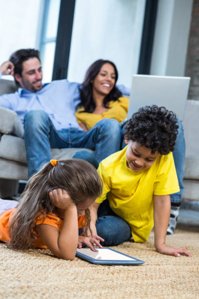 istock Children laying on the carpet using tablet in living room 665554982