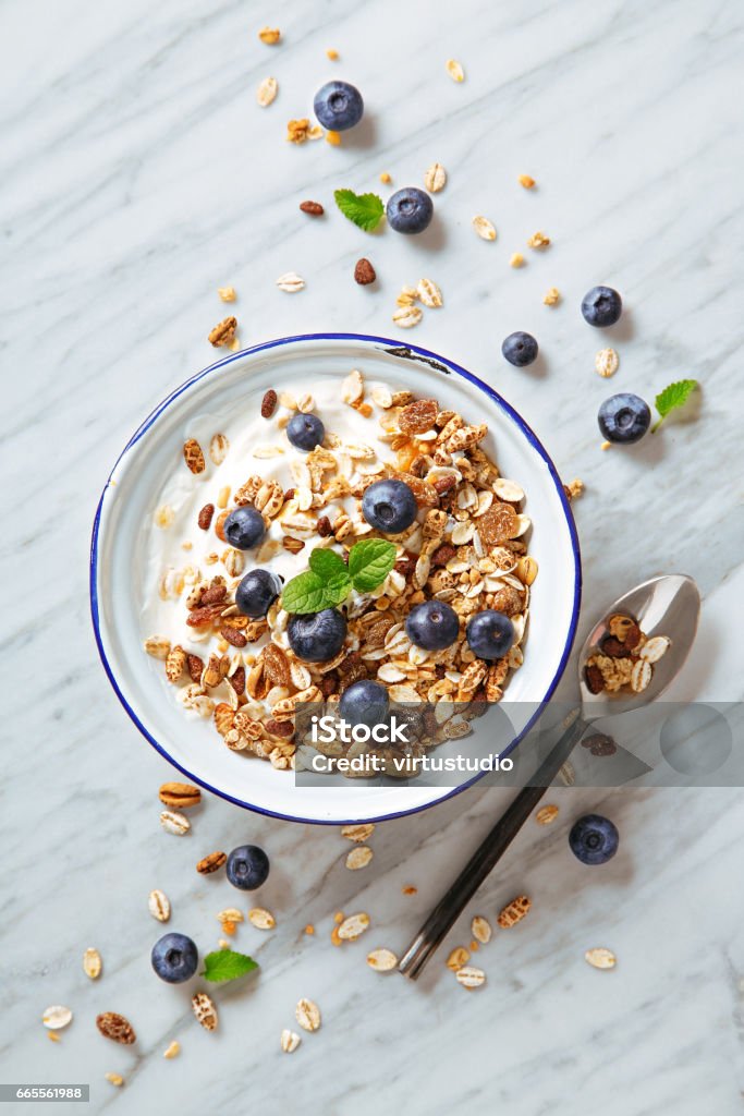 Desayuno de cereales con arándanos sobre fondo de mármol. Comida saludable por la mañana con bayas frescas. Vista superior - Foto de stock de Muesli libre de derechos