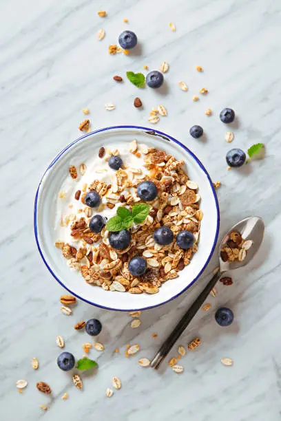 Photo of Cereals breakfast with blueberries on a marble background. Healthy morning meal with fresh berries. Top view