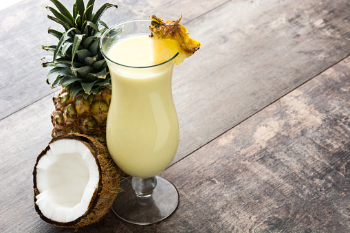 Piña colada cocktail and pineapple fruit on wooden background