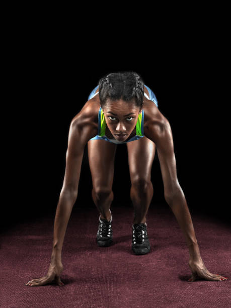 Beautiful athlete on a race track is ready to run The young african athlete on a race track is ready to run on black sprint stock pictures, royalty-free photos & images