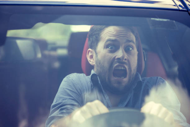Young man driving a car shocked about to have traffic accident, windshield view