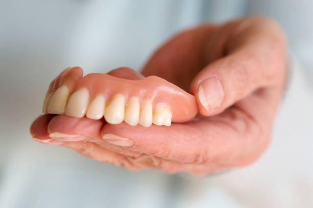 istock closeup of womans hand holding a teeth denture 665575194