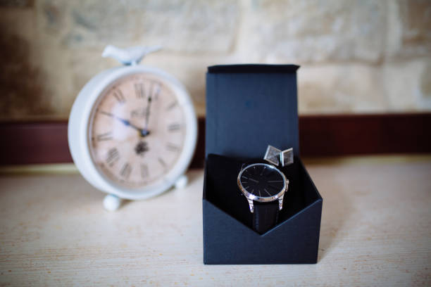 istock Wedding accessories. Watches and cufflinks on white textured table and clock on the background 665578068