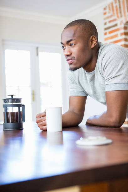 istock Young man leaning on the table holding coffee mug 665586212