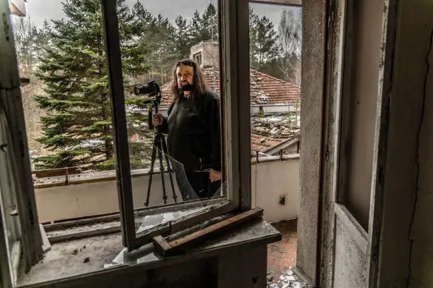 Photo of Mature man, 50 years old Caucasian with the beard and long hairs, photographer, shooting abandoned resort in Belarus